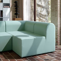 Mint green modular sofa with soft, rounded edges and a textured fabric against a brick floor.