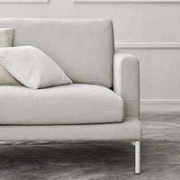 Light gray sofa with smooth fabric and subtle texture, accented by soft beige and white pillows. Modern minimalistic design.