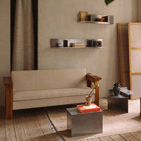 Beige sofa with wooden arms, silver accent tables, and warm, neutral decor in a cozy, modern living space.