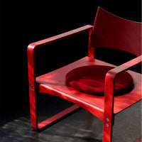 Bright red chair with a circular crimson cushion, set against a dark backdrop, showcasing sleek lines and modern design.