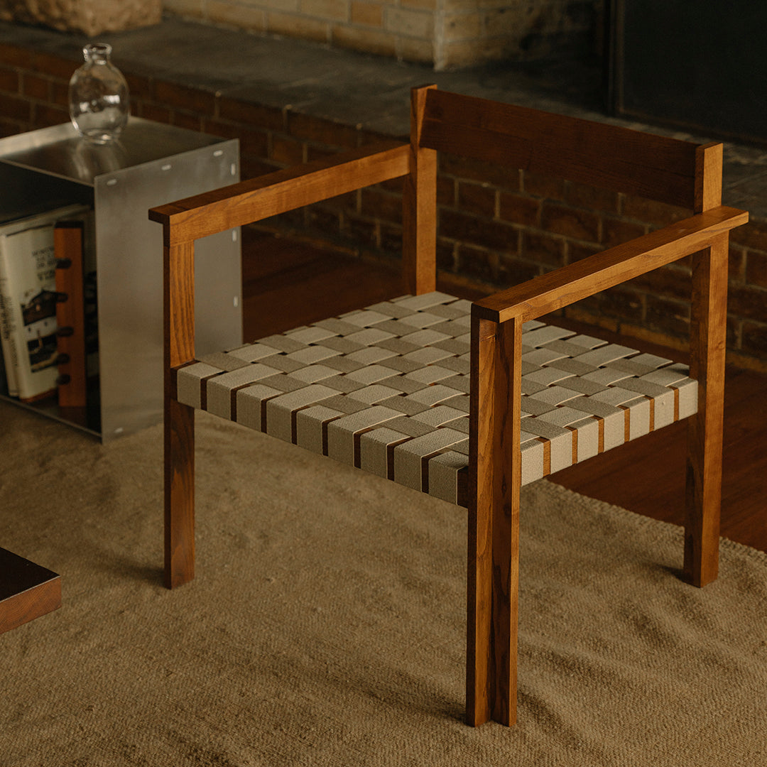 Wooden chair with a geometric beige and white pattern on the seat, complemented by rich brown armrests and frame.