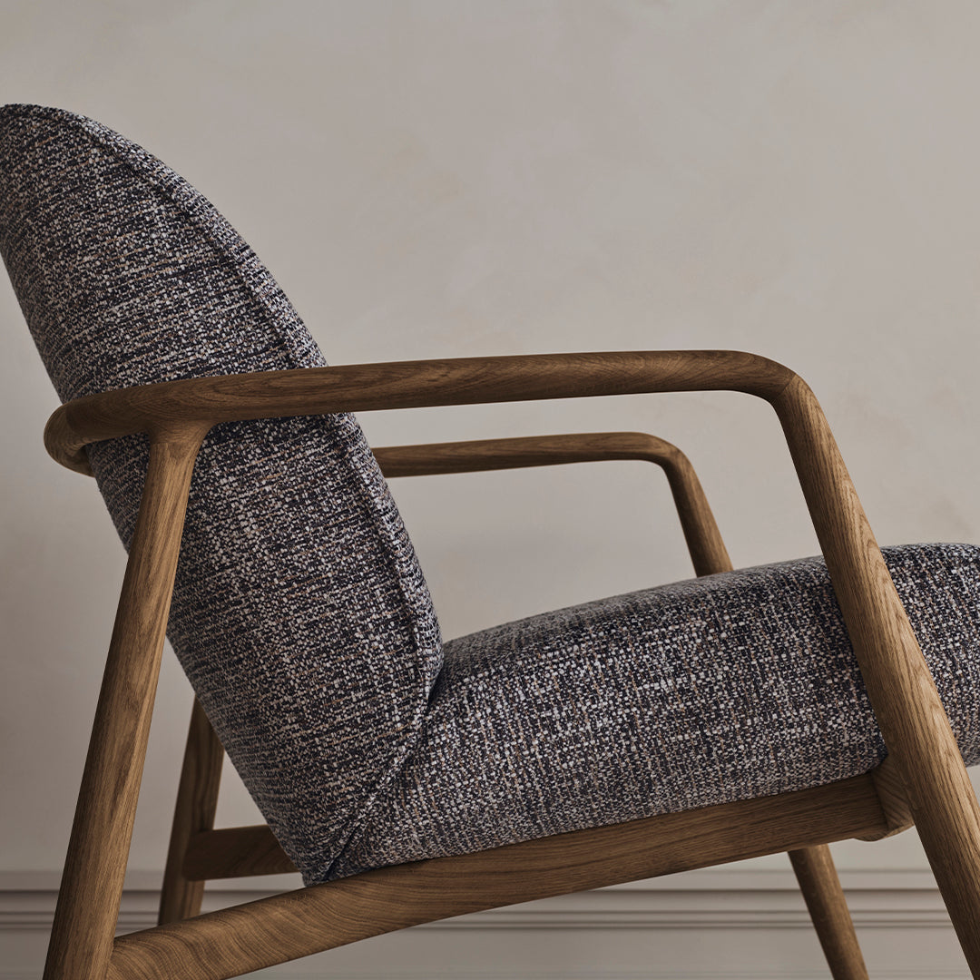 Mid-century armchair featuring a textured dark blue and grey patterned fabric with natural wood legs.