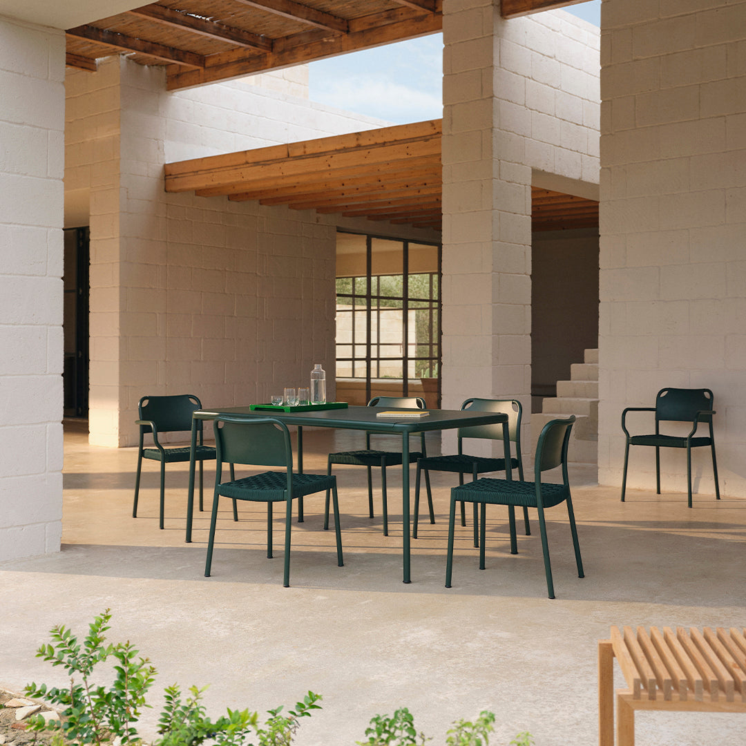 Green outdoor dining set with sleek chairs and a rectangular table, featuring a minimalist design against a neutral backdrop.