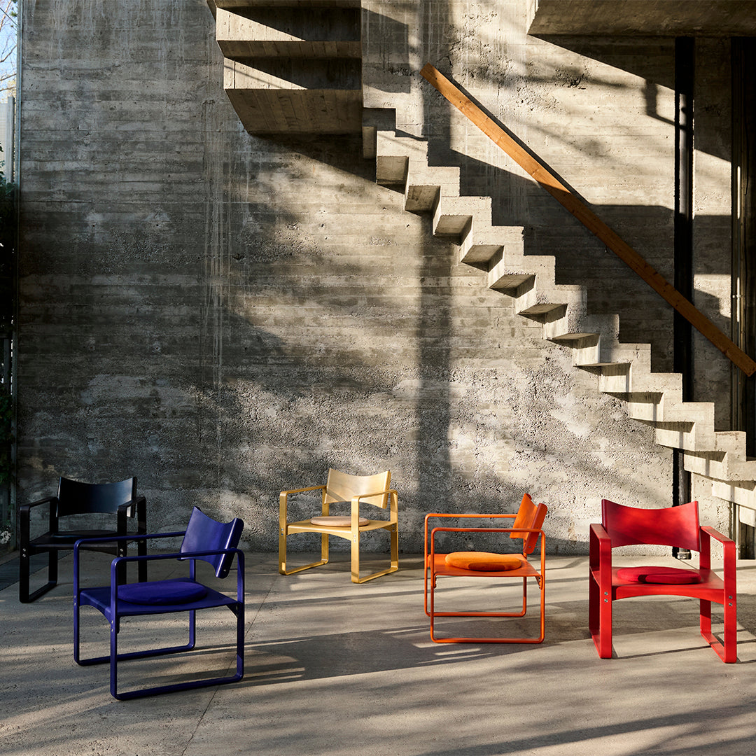 Multi-colored chairs: black, yellow, red, orange, and purple against a textured concrete backdrop. Modern, vibrant design.
