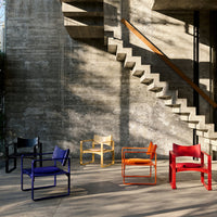 Multi-colored chairs: black, yellow, red, orange, and purple against a textured concrete backdrop. Modern, vibrant design.