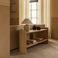 Light wood console table with smooth curves, neutral tones, and minimalistic decor against soft beige walls.