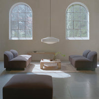 Modern living room featuring grey and brown sofas, minimalist decor, and natural light from arched windows.