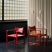"Modern chairs in vibrant red and orange hues with sleek lines and minimalistic design, set against a light backdrop."