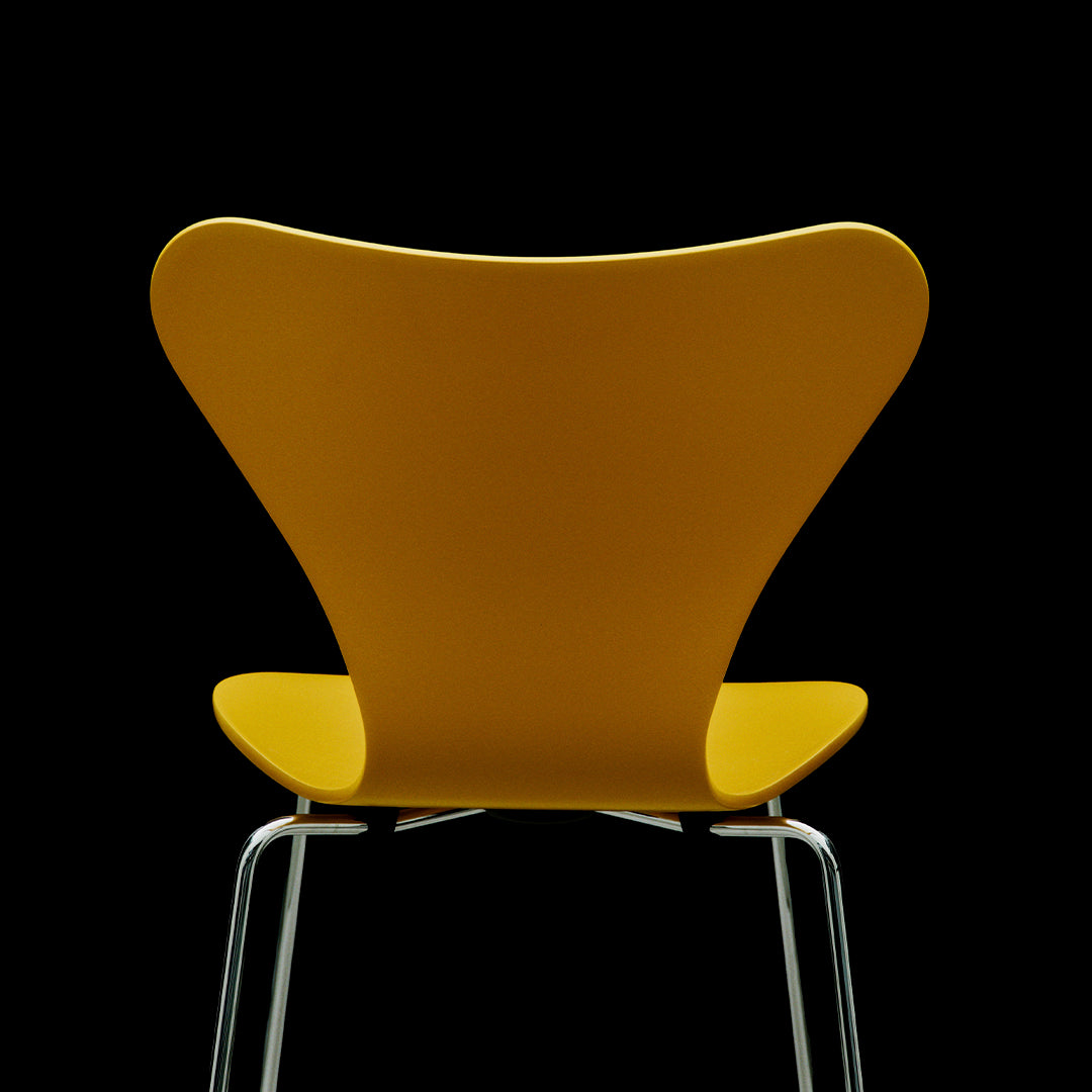 Bright yellow chair with a unique butterfly shape against a black background. Sleek chrome legs add a modern touch.