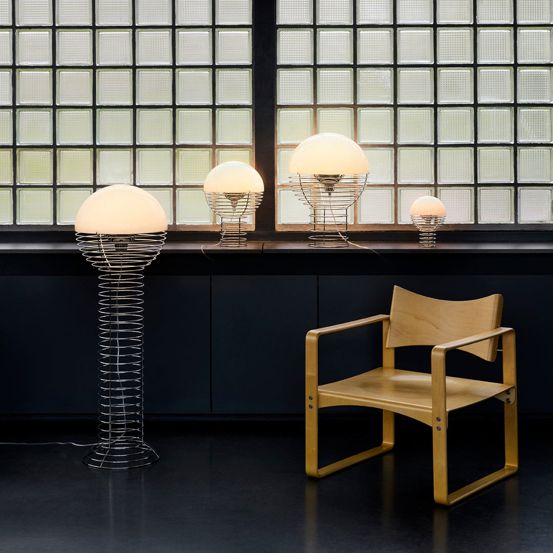 "Modern lamp collection featuring round white shades and metallic wire bases, paired with a natural wood chair."
