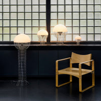 "Modern lamp collection featuring round white shades and metallic wire bases, paired with a natural wood chair."