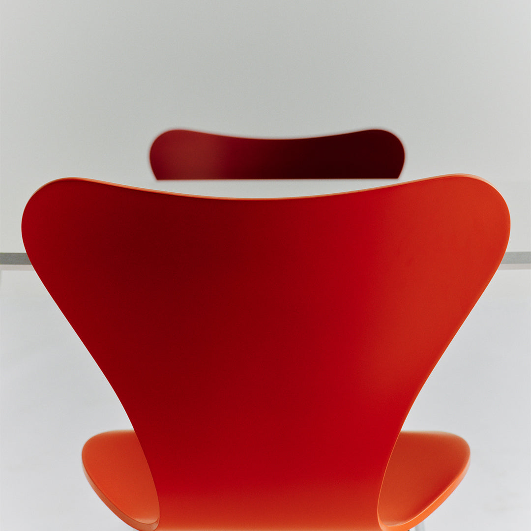 Red modern chair with sleek, curved design and smooth, glossy finish. Perfect for stylish interiors.