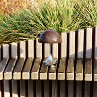 Modern table lamp featuring a sleek chrome base and a rich brown mushroom-shaped shade, set against wooden slats.