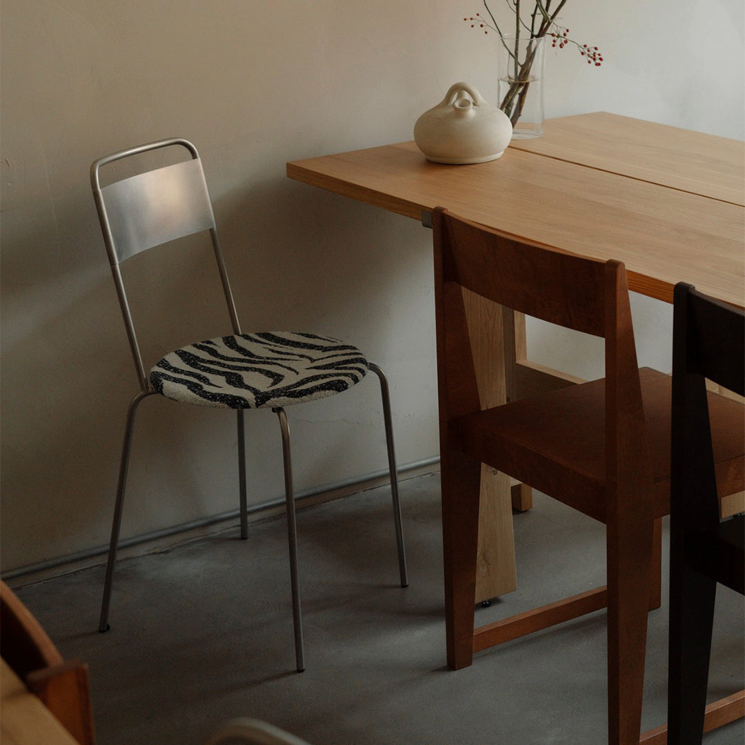 "Modern chair with a zebra-patterned seat in a minimalist wood and neutral-toned setting."