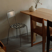 "Modern chair with a zebra-patterned seat in a minimalist wood and neutral-toned setting."