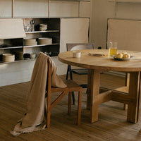 Neutral-toned wooden dining table with warm beige linen, complemented by subtle dishware in soft earthy colors.