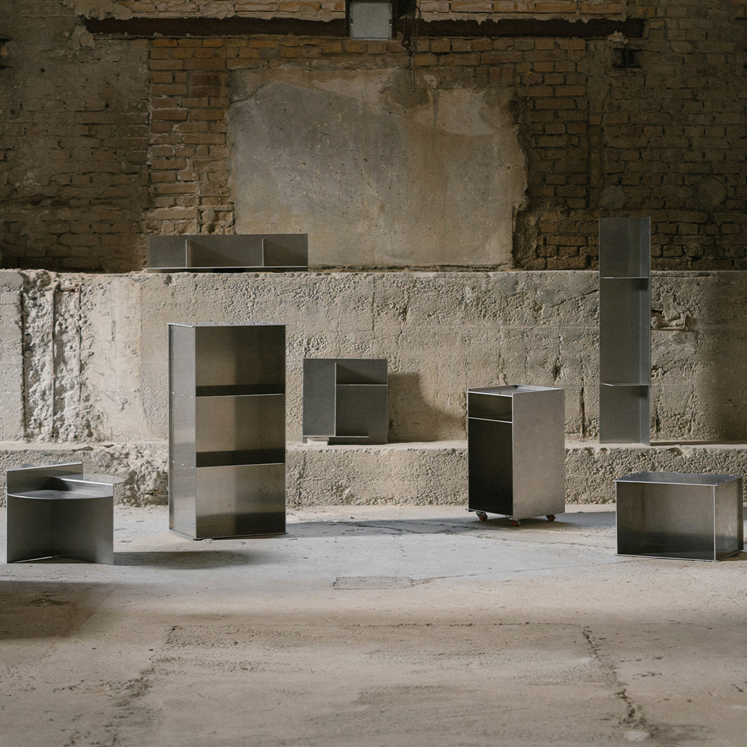 Modern metallic furniture in various geometric shapes, featuring a sleek silver finish and minimalist design.