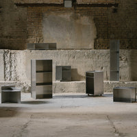 Modern metallic furniture in various geometric shapes, featuring a sleek silver finish and minimalist design.