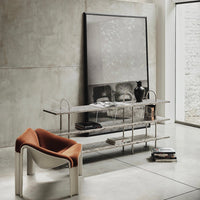 Modern gray concrete wall, sleek metal shelving, and an orange armchair create a stylish, minimalist aesthetic.