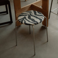 Zebra-patterned stool with black and white colors, featuring a sleek metallic frame.