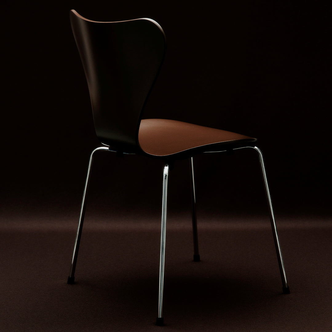 Black and brown chair with a sleek design and shiny chrome legs, set against a dark background.