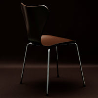 Black and brown chair with a sleek design and shiny chrome legs, set against a dark background.
