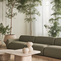 Sleek green sofa with textured fabric, complemented by beige ceramic vases and marble coffee table in a serene setting.