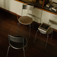 Set of three modern chairs featuring black, beige, and metallic finishes on a dark wooden floor. Minimalist design.