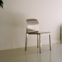 Sleek silver metal chair with a minimalist design, smooth finish, and no visible patterns against a neutral background.