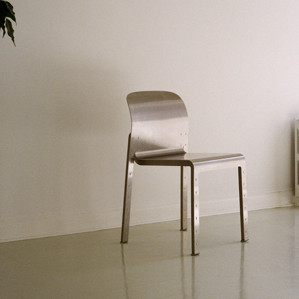 Sleek silver metal chair with a minimalist design, smooth finish, and no visible patterns against a neutral background.