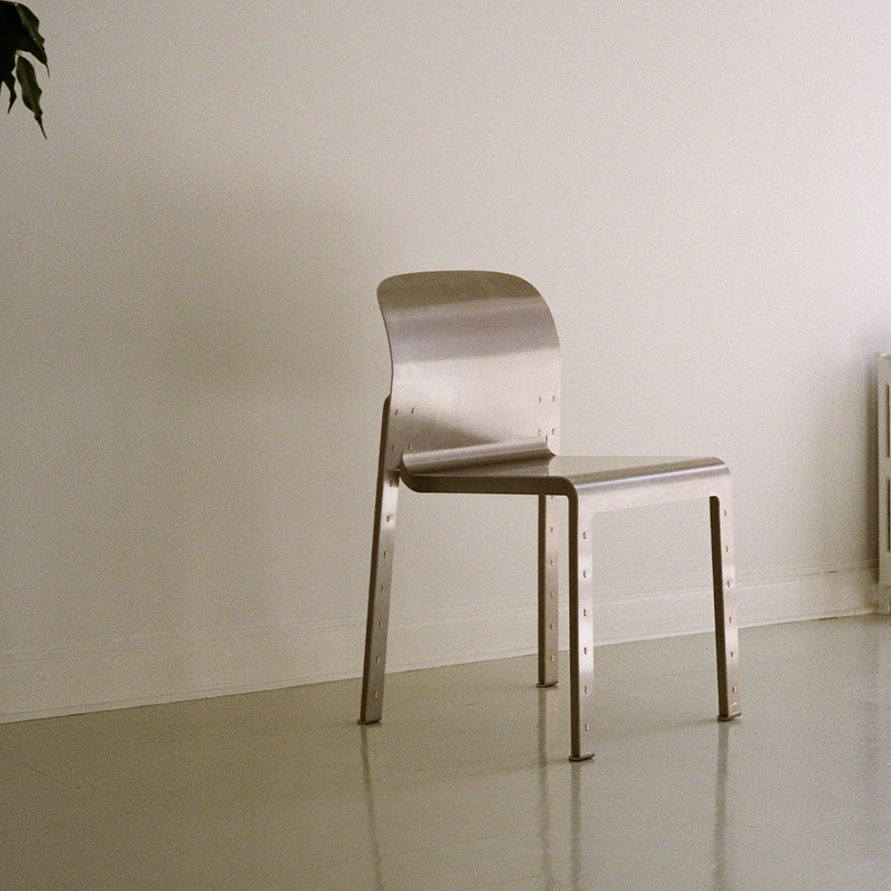 Sleek silver metal chair with a minimalist design, smooth finish, and no visible patterns against a neutral background.