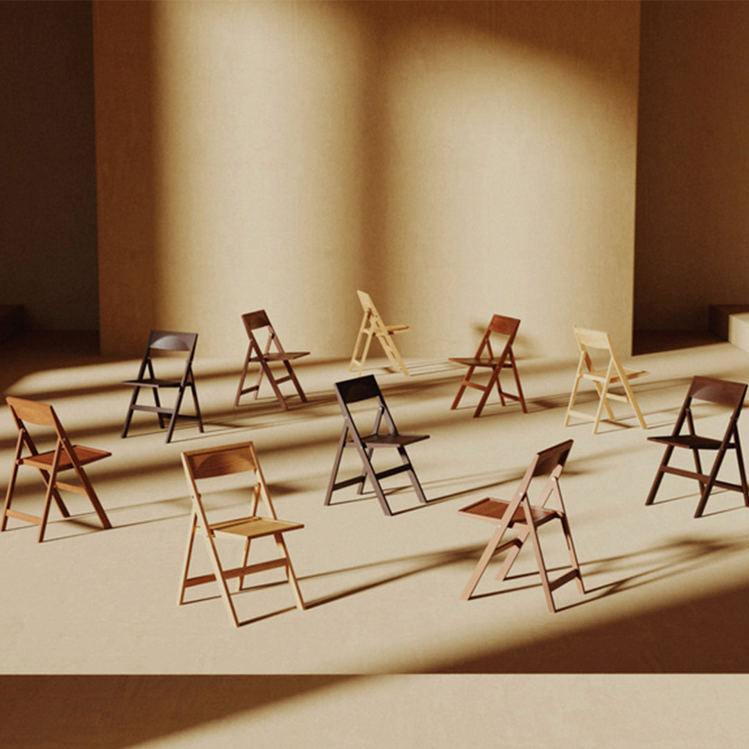 Set of wooden folding chairs in various natural tones arranged in a warm, minimalist setting with soft shadows.