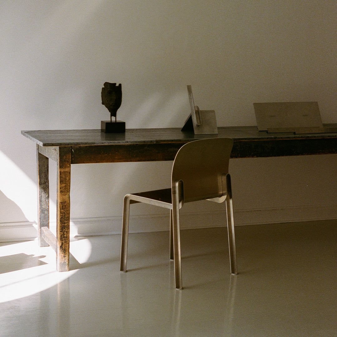 Minimalist desk with a metallic chair, featuring neutral tones and soft shadows for a modern aesthetic.