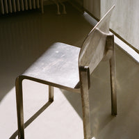 Sleek silver metal chair with smooth, minimalist design and subtle reflections in natural light.