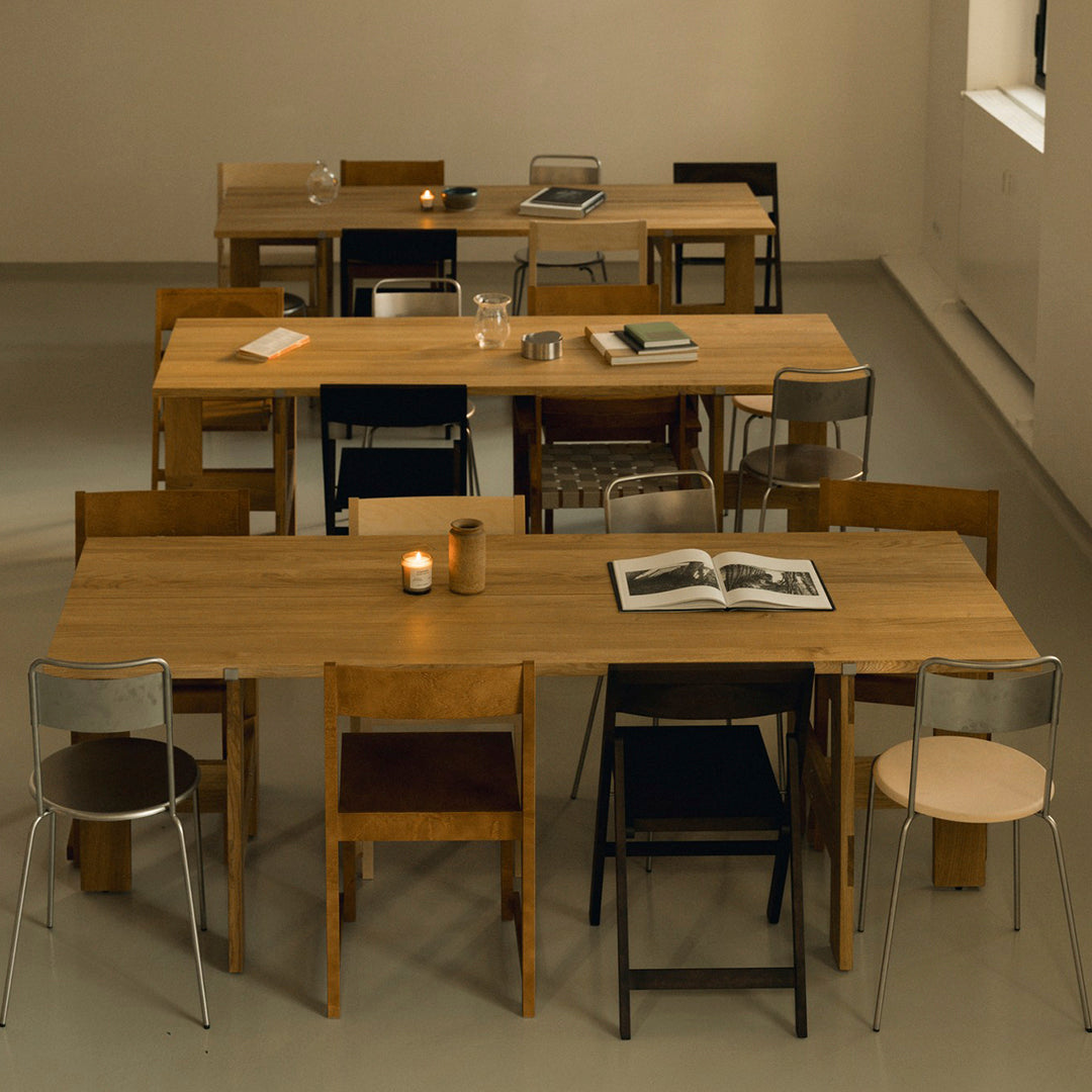 Wooden dining tables with varied black, brown, and natural wood chairs in a modern setting. Stylish and minimalistic design.