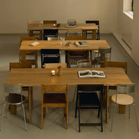 Wooden dining tables with varied black, brown, and natural wood chairs in a modern setting. Stylish and minimalistic design.