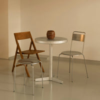 Metallic silver table with wooden and metal chairs against a soft beige background, creating a modern minimalistic look.