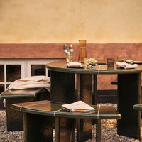 Green table and stools with a glossy finish, accented by subtle lighter lines, set against a warm, earthy background.