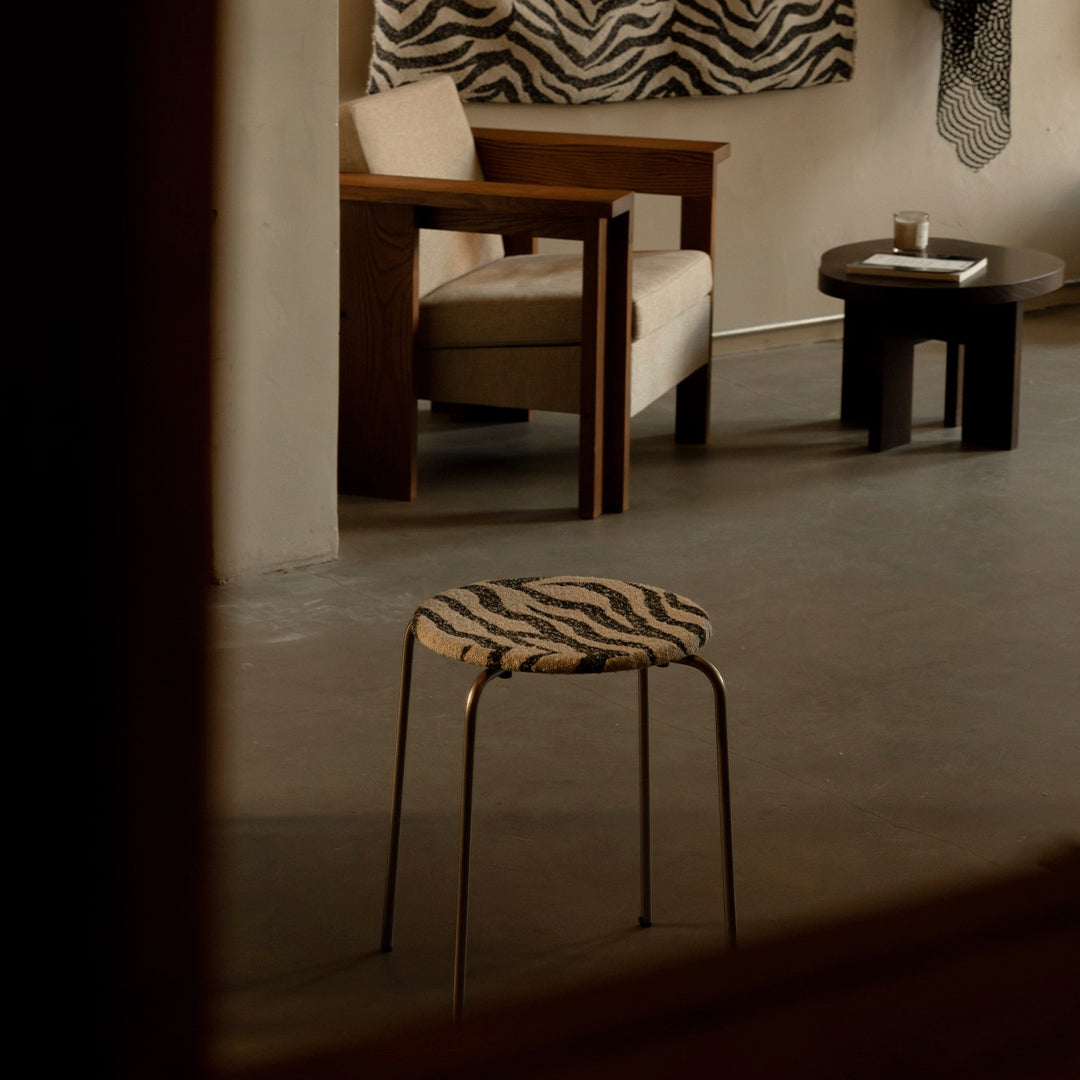 Zebra-patterned stool with a round seat and metal legs, featuring bold black and white colors. Minimalistic design for modern interiors.