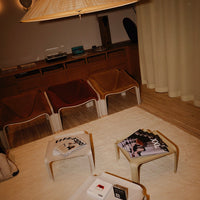 "Modern lounge area with earthy tones, textured fabric chairs, and geometric patterned magazines on light-colored tables."