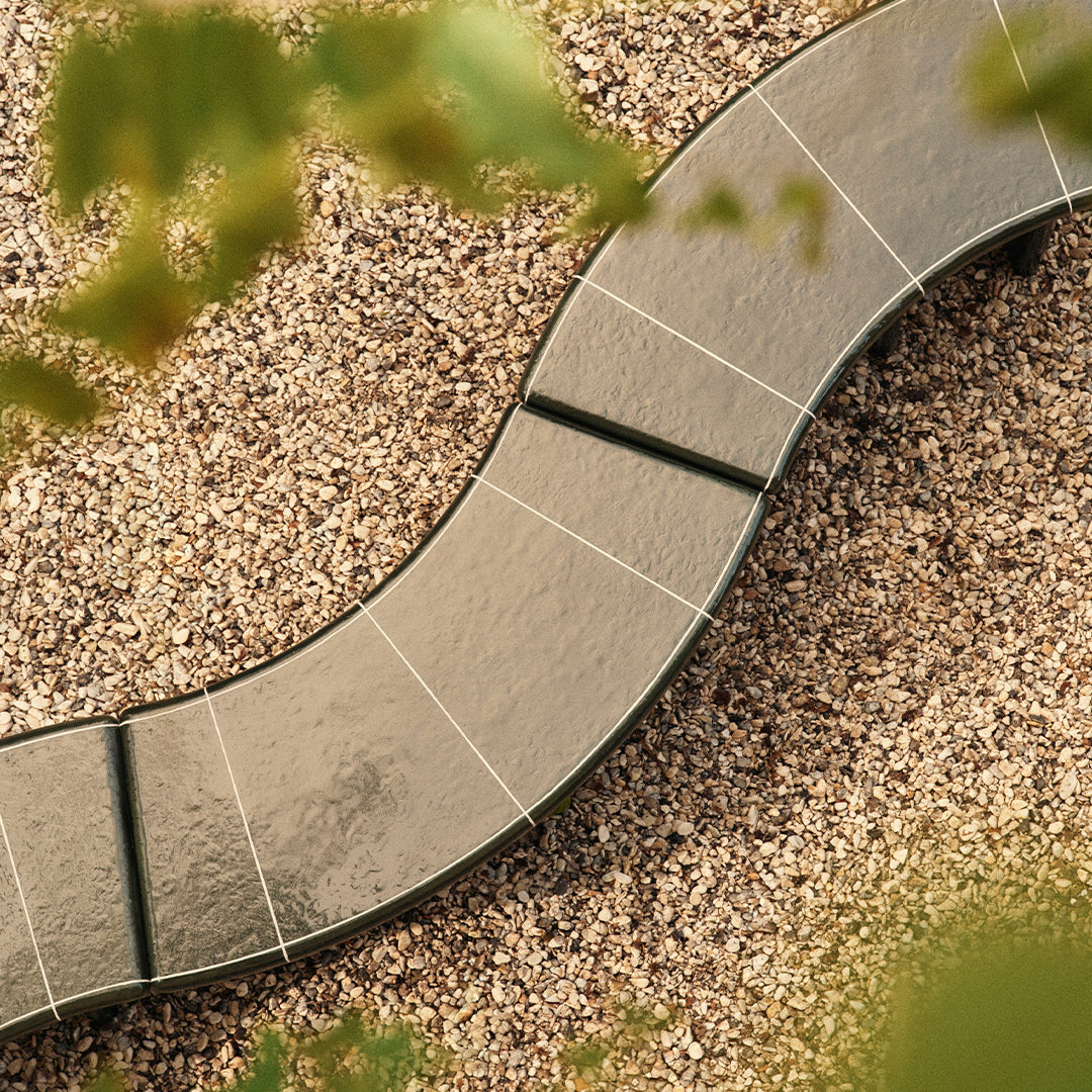 Curved gray stepping stones on a bed of fine gravel, with soft green foliage in the background.