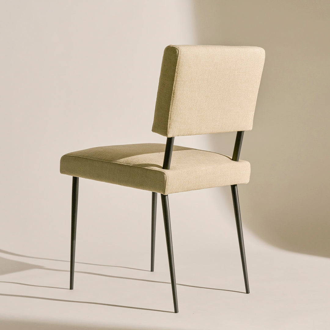 Beige upholstered chair with sleek black metal legs, featuring a minimalist design and subtle texture.