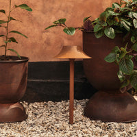 Terra-cotta lamp on a rustic garden background, featuring earthy brown tones and smooth, minimalist design.