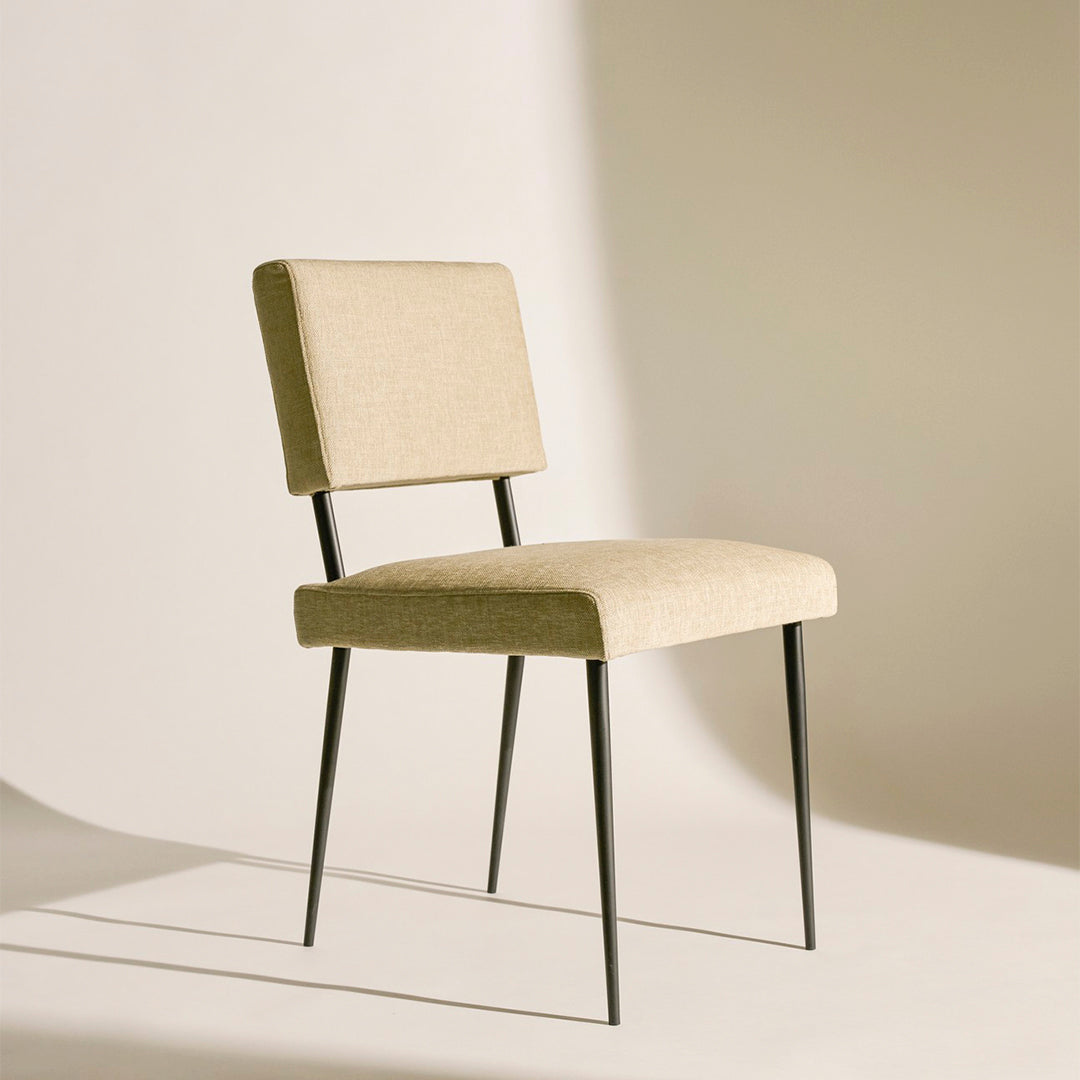 Beige upholstered chair with a minimalist design and sleek black metal legs, perfect for modern decor.