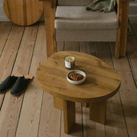 Wooden coffee table with a natural, rounded shape and warm brown tones, set on light wooden flooring.