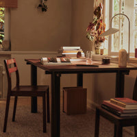 Warm brown wooden table with matching chair, surrounded by neutral tones and soft textures. Perfect for cozy spaces.