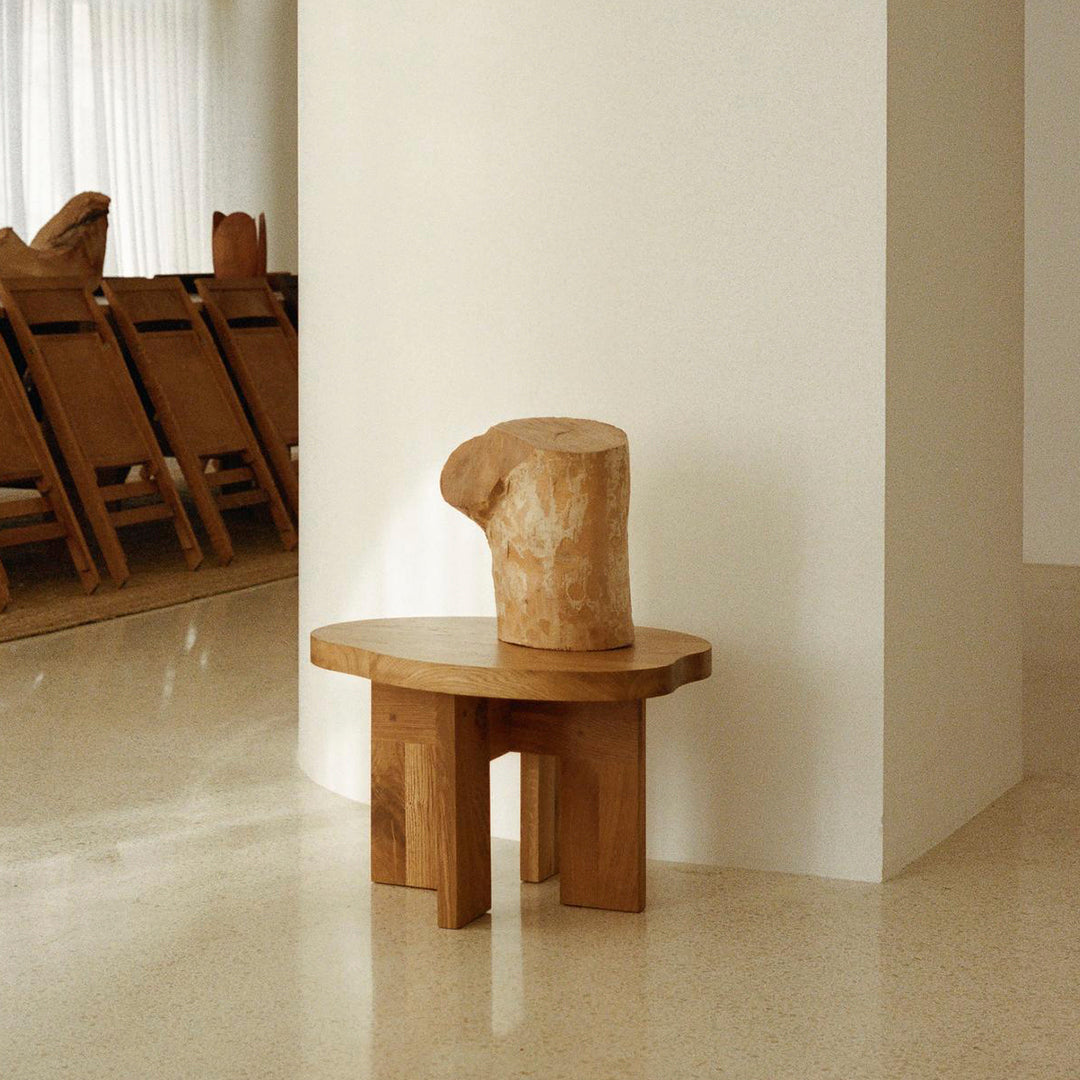 Natural wood accent table with a smooth grain finish, featuring a light brown color and organic, sculptural shape.