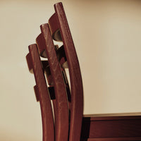 "Close-up of rich burgundy wooden chair legs against a neutral backdrop, showcasing elegant curved patterns."