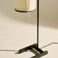 Minimalist black floor lamp with a cream fabric shade and subtle texture. Sleek, modern design for contemporary decor.