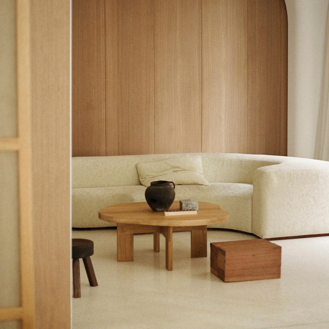 Beige textured sofa, natural wood coffee table, and earthy pottery; warm tones with minimalistic design elements.